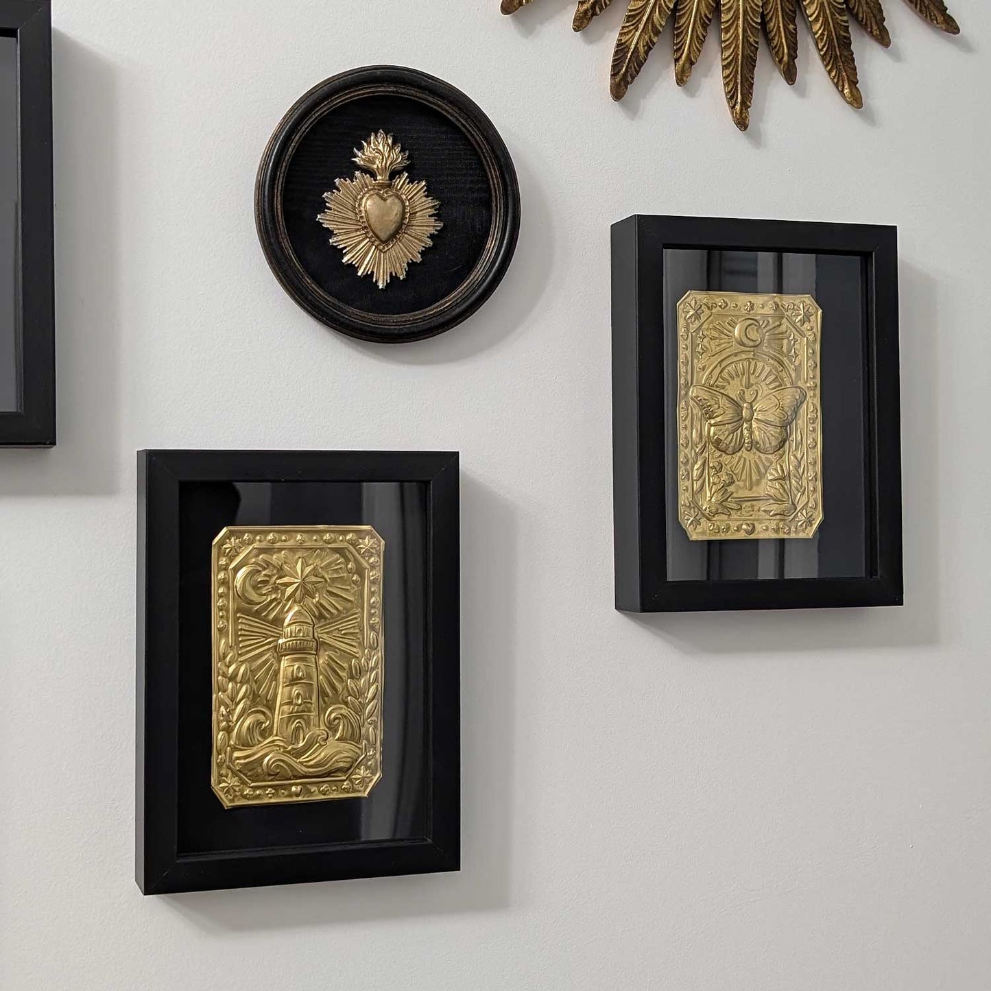 Ex-voto mural fait main avec phare, branches d’olivier et rayons lumineux
Détail du talisman mural Le Phare Intérieur en métal repoussé
Talisman mural symbolique accroché au mur dans son cadre doré