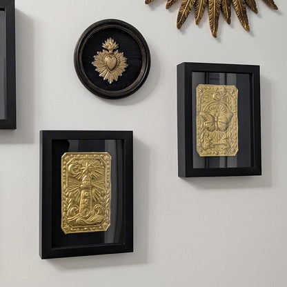 Ex-voto mural fait main avec phare, branches d’olivier et rayons lumineux
Détail du talisman mural Le Phare Intérieur en métal repoussé
Talisman mural symbolique accroché au mur dans son cadre doré